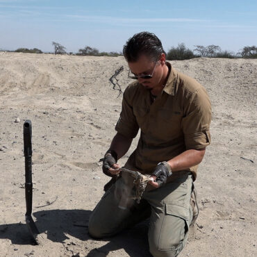Timothy Alberino holding a Paracas burial cloth in the desert of Paracas, Peru.